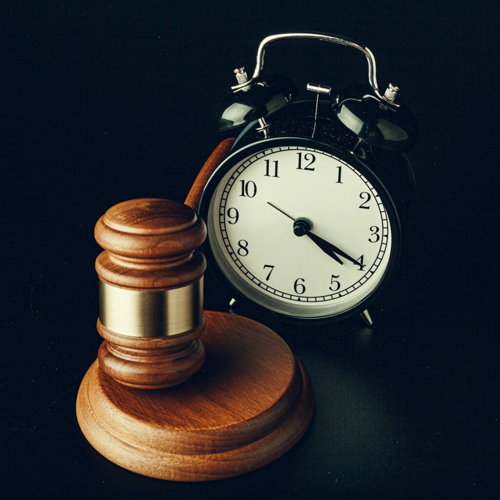 Wooden judge hammer with alarm clock on black background